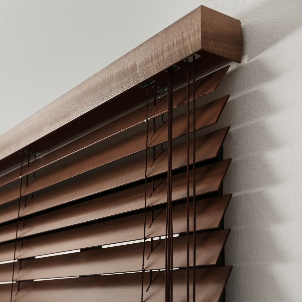 Close-up of dark stained wood blinds with horizontal slats and pull cords, mounted against a neutral wall, highlighting texture and craftsmanship.